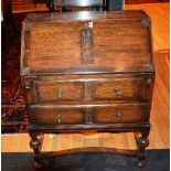 An oak writing bureau, the hinged writing flap enclosing pigeon holes above two drawers,