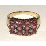 A 9ct gold pink topaz and diamond ring, the 12 oval cut topaz' in grid formation,