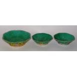 Three Chinese glazed pottery dishes, decorated with colourful panels of symbols on green ground,