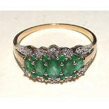 A 9ct gold emerald and diamond ring, set with five graduated oval cut emeralds to centre,