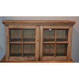 A pine display cabinet top, with two glazed doors, enclosing shelved interior,