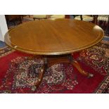 A good reproduction circular dining table, raised on four turned pillars and platform base,