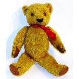 An early 20th century 'Chad Valley' plush teddy bear, wearing a red ribbon,