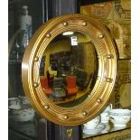 A convex circular wall mirror, decorated with ball roundels,