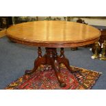 A Victorian mahogany snap top loo table, the oval top raised on quadripartite scroll supports,