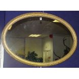 A giltwood oval wall mirror, with moulded beading and pine backing,