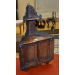 An oak wall mounting corner cabinet, with raised shelf above cupboard doors to front,