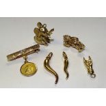 A collection of gold charms, one 18ct gold charm of a winged putti on brooch, stamped 750,