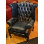 A Chesterfield blue leather wing back armchair,