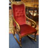 A Victorian walnut rocking chair, with scroll arm rests, upholstered in later red buttonback velour,