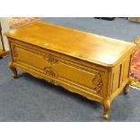 An oak blanket box, with hinged top above carved panels, raised on scroll supports,