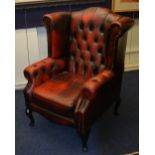A Chesterfield ox blood leather wing armchair, raised on cabriole supports,