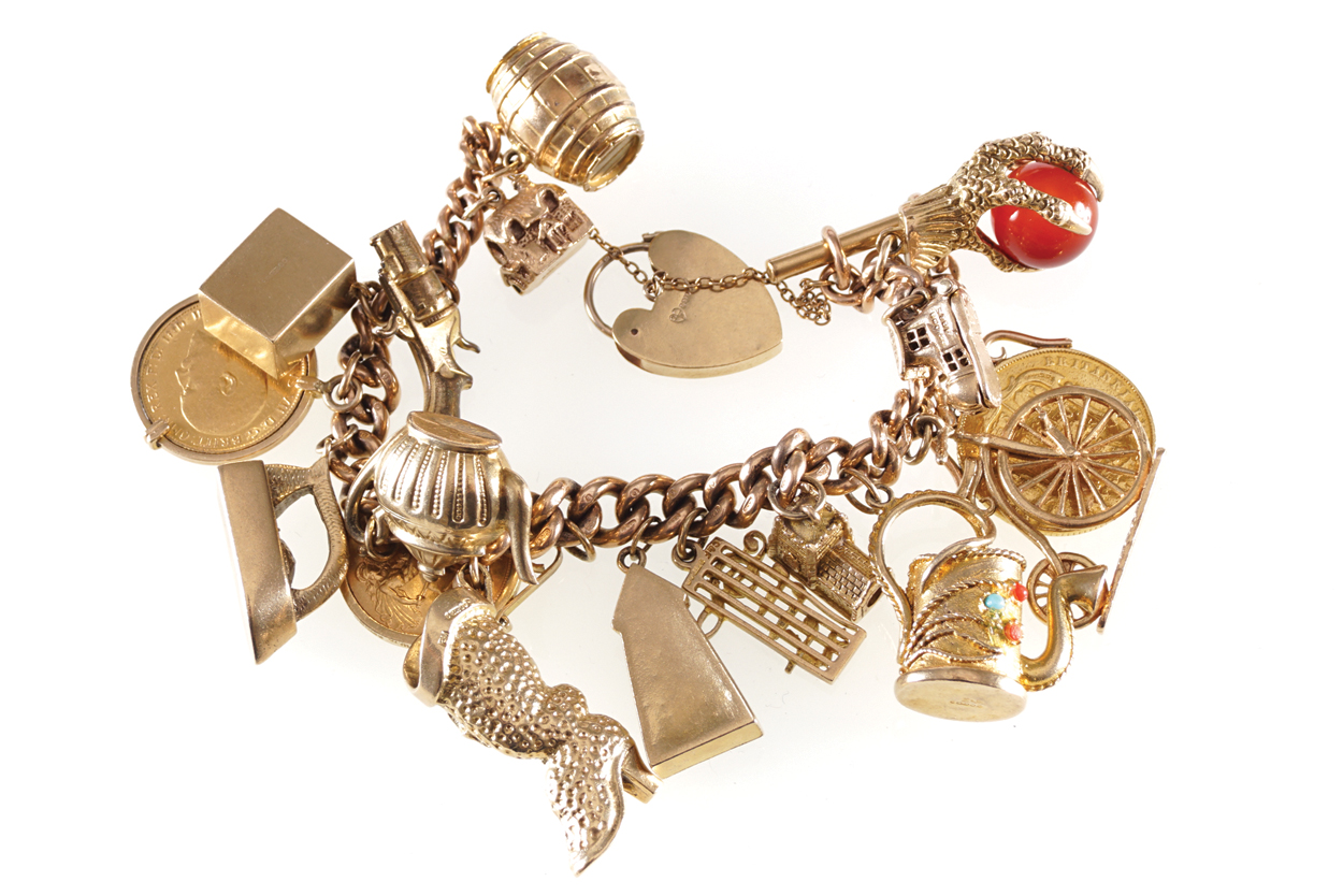 LADIES 9CT. ROSE GOLD GRADUATED CURB CHARM BRACELET with 17,9ct yellow gold charms, and a padlock