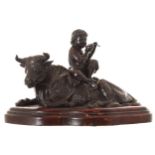 CHINESE BRONZE FIGURE seated on a cow, mounted on a wooden base 26 cm. wide