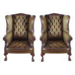 PAIR OF MAHOGANY AND HIDE UPHOLSTERED WING BACK ARMCHAIRS each with a deep button back, and seat,