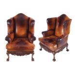 PAIR OF DUBLIN EDWARDIAN PERIOD CARVED MAHOGANY AND HIDE UPHOLSTERED WING ARMCHAIRS each raised on