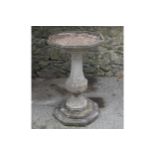 EDWARDIAN MOULDED STONE BIRD BATH of hexagonal form, raised on a chamfered baluster stem and