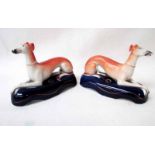 A pair of 19th century Staffordshire pottery Quill Holders modelled as recumbent Greyhounds with