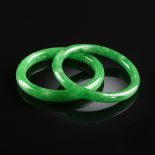 A GROUP OF TWO CHINESE JADEITE JADE BANGLES, MODERN, each of apple green color with white inclusions