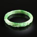 A CHINESE JADEITE JADE CARVED BANGLE, MODERN, of celadon color with apple green inclusions and