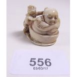A Japanese Meiji period ivory netsuke carved seated old man in a wash tub with boy scrubbing his