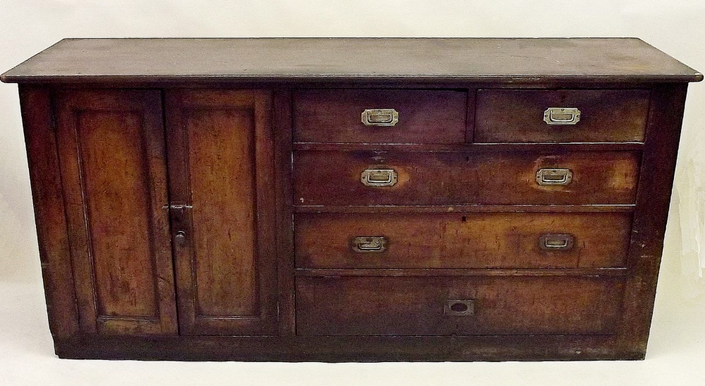 An early 19th century pine side cabinet with cupboard and drawers with military style brass handles,