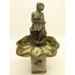 A stone finish bird bath and fountain with seated girl in a shell
