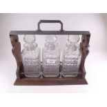 A three bottle oak tantalus - one decanter cracked