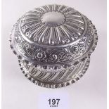 A silver circular dressing table box with all over embossed decoration - London 1887, 180g