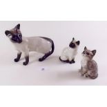 A large Beswick Siamese cat, smaller Siamese and one other Beswick cat