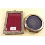 A circular silver photo frame 13.5cm and a rectangular silver frame with embossed scrollwork