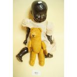 A black plastic doll and a small gold jointed teddy bear