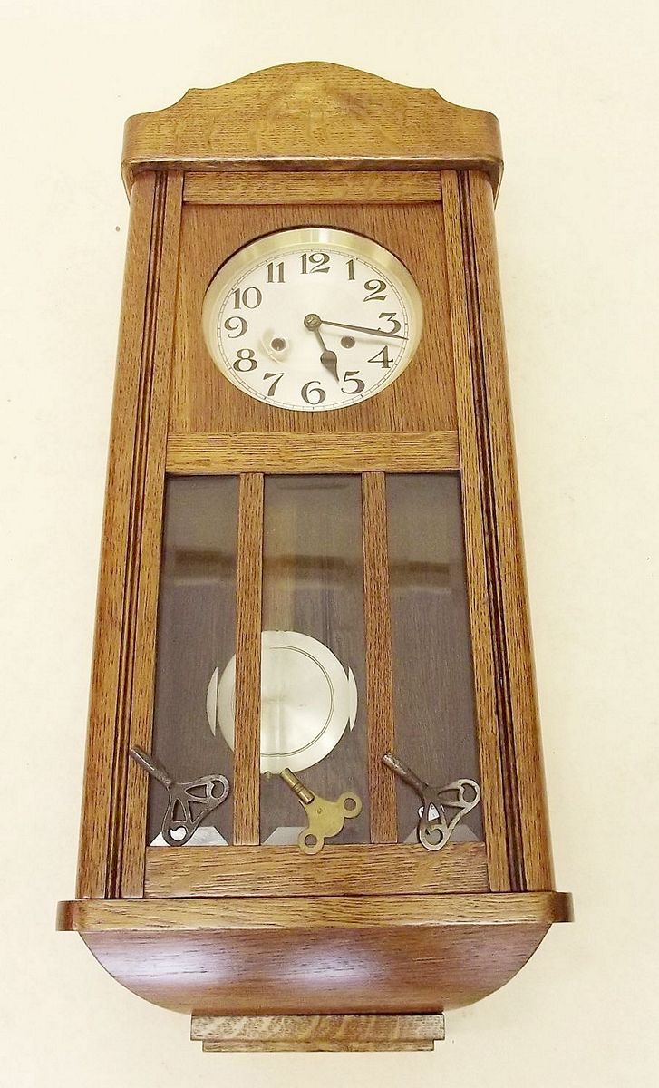 A 1930's oak wall clock with glazed door