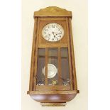 A 1930's oak wall clock with glazed door