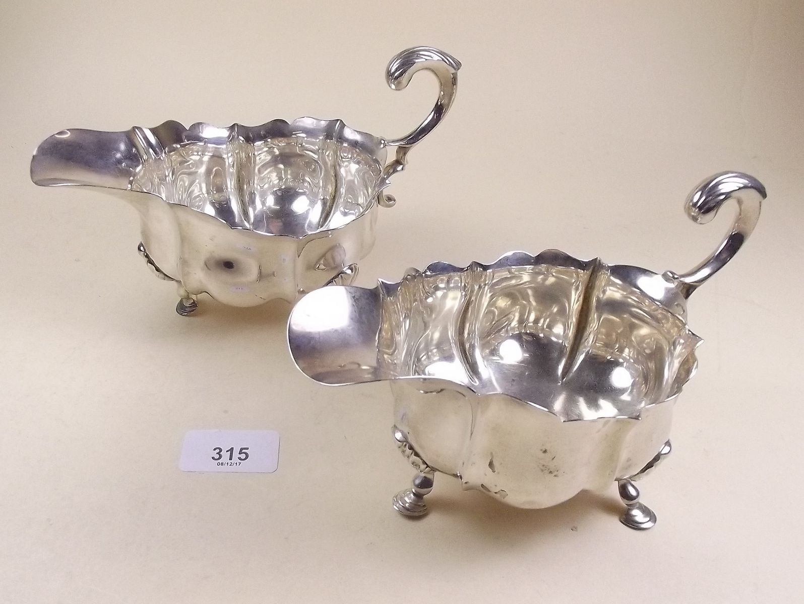 A pair of silver frilled top and serpentine moulded sauce boats with hoof feet, London 1902 and 1909