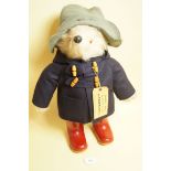 A Gabrielle Paddington Bear in navy blue coat and red Dunlop boots - good condition