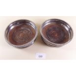 A pair of silver plated and turned wood bottle coasters