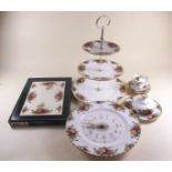 A Royal Albert clock, cake stand, butter dish, table mats, two bon bon dishes and covered sugar