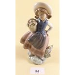 A Lladro figure of a girl holding a basket of flowers - boxed