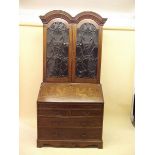 An early 19th century Dutch double dome top bureau bookcase, the two glazed doors with scrollwork