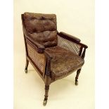 A Regency mahogany framed cane and leather library chair on turned supports and large castors