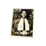 Muhammad Ali, an autographed photograph of Ali holding a championship belt. The photograph was