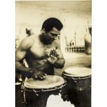 Muhammed Ali, an autographed photograph (slightly faded autograph) of Ali playing Afican drums.