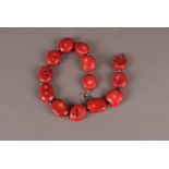 A red coral bead necklace, the large sweet shaped beads are separated by tooled white metal