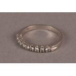 A modern white metal and diamond half hoop eternity ring, set with a row of nine brilliant cuts,