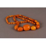 An Art Deco period amber necklace, having graduating toffee and caramel coloured oval beads, largest