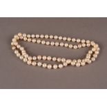 A single string pearl necklace, the long knotted cotton with uniform white pearls and having a