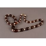 A long modern Baltic amber and pearl necklace, on knotted string with a yellow metal pearl and