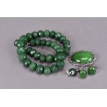 A suite of jade jewels, including a faceted bead necklace, a pair of earrings an oval brooch and a