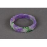 A carved jade bangle, the stained purple and mauve circular bangle carved with dragon design 7.5cm